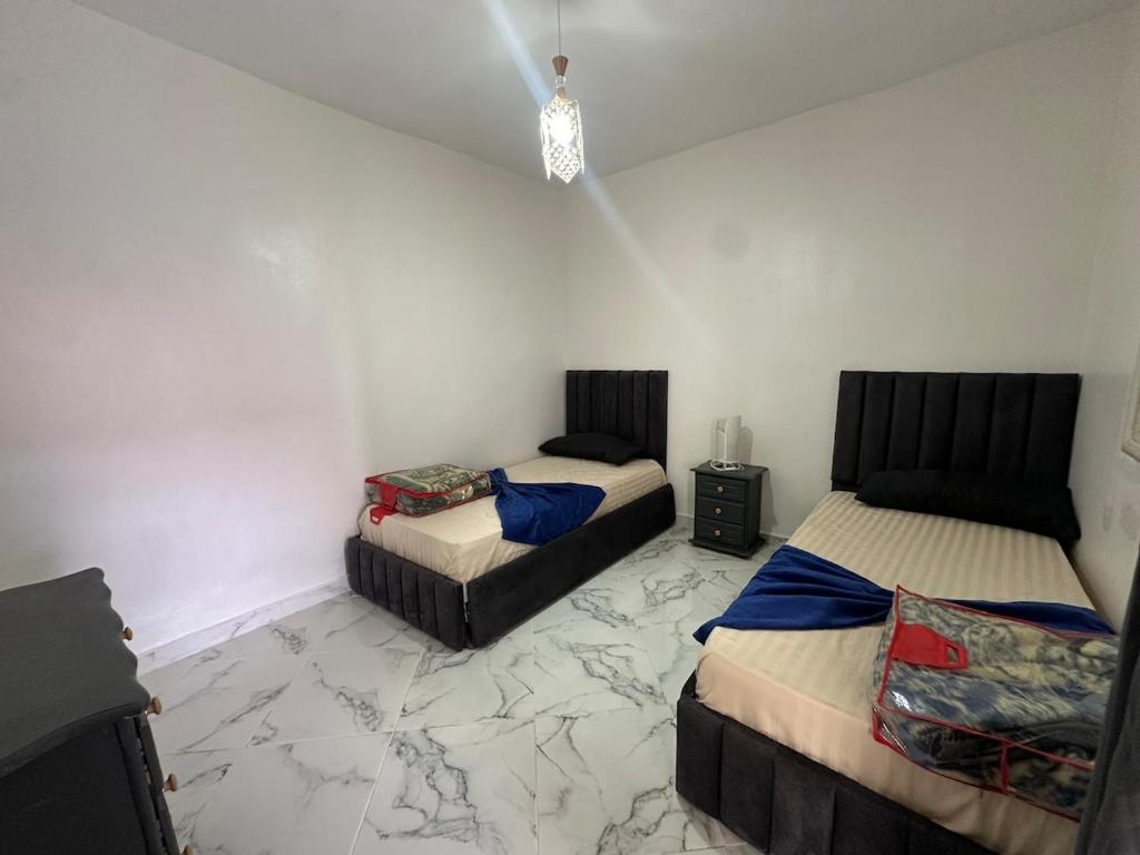 1 dormitorio con 2 camas y suelo de mármol en A unique and cute apartment in a prime location, en Er Rachidia