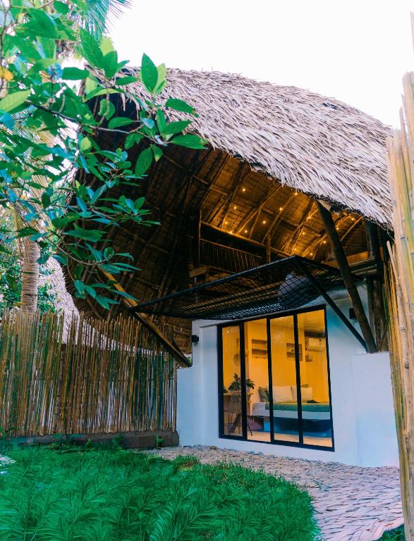 a house with a thatched roof and windows at Bamboo Jungle Villa's in El Nido
