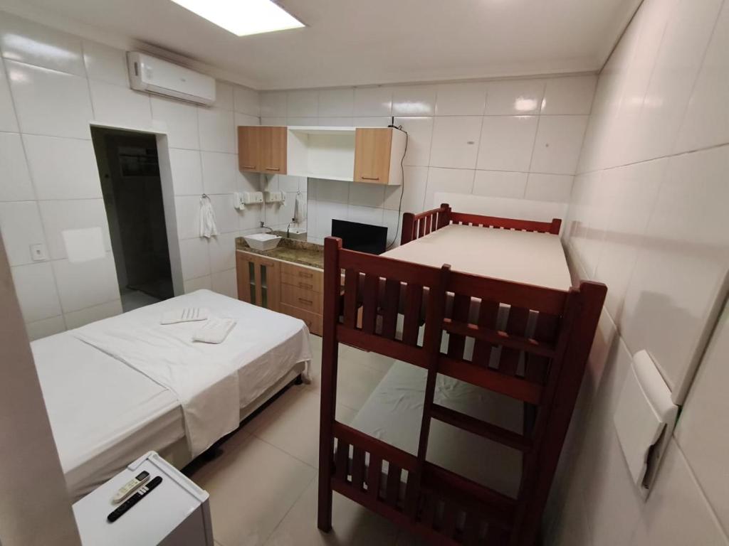 a small room with two beds and a kitchen at Essenza Suites Natal in Natal