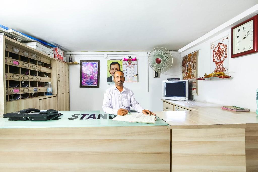 a man sitting at a stand sign in a room at SPOT ON Standard in Jabalpur