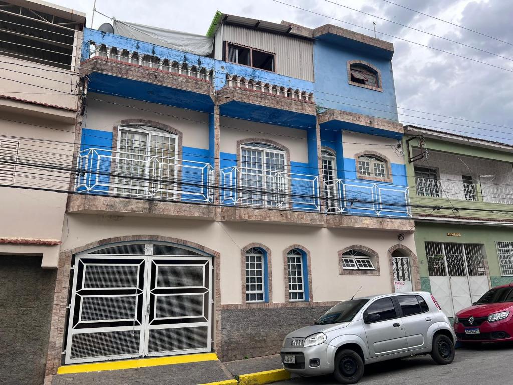 ein blau-weißes Haus mit einem Auto vor dem Haus in der Unterkunft Casa Nhá Chica - Aparecida - a 10 minutos a pé do Santuário Nacional in Aparecida