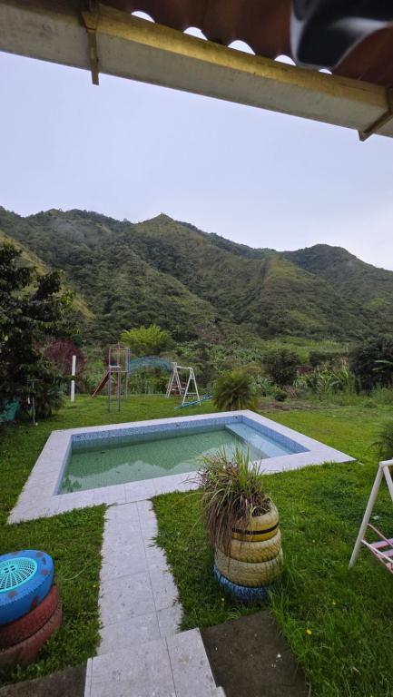 a swimming pool in a yard with a mountain in the background at Cabaña rústica con encanto y luces cálidas para noches inolvidables in Apuela