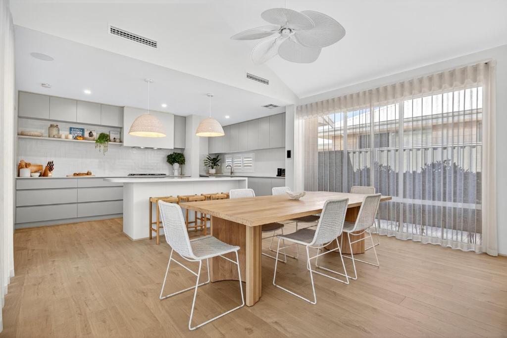 a kitchen and dining room with a wooden table and chairs at Coastal Luxe 4-Bed House in Madora Bay in Singleton