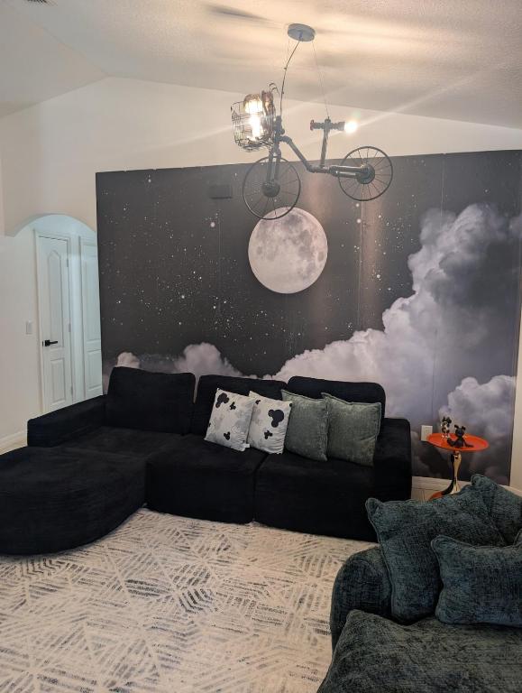 a living room with a black couch and a wall with clouds at Magical World in Davenport