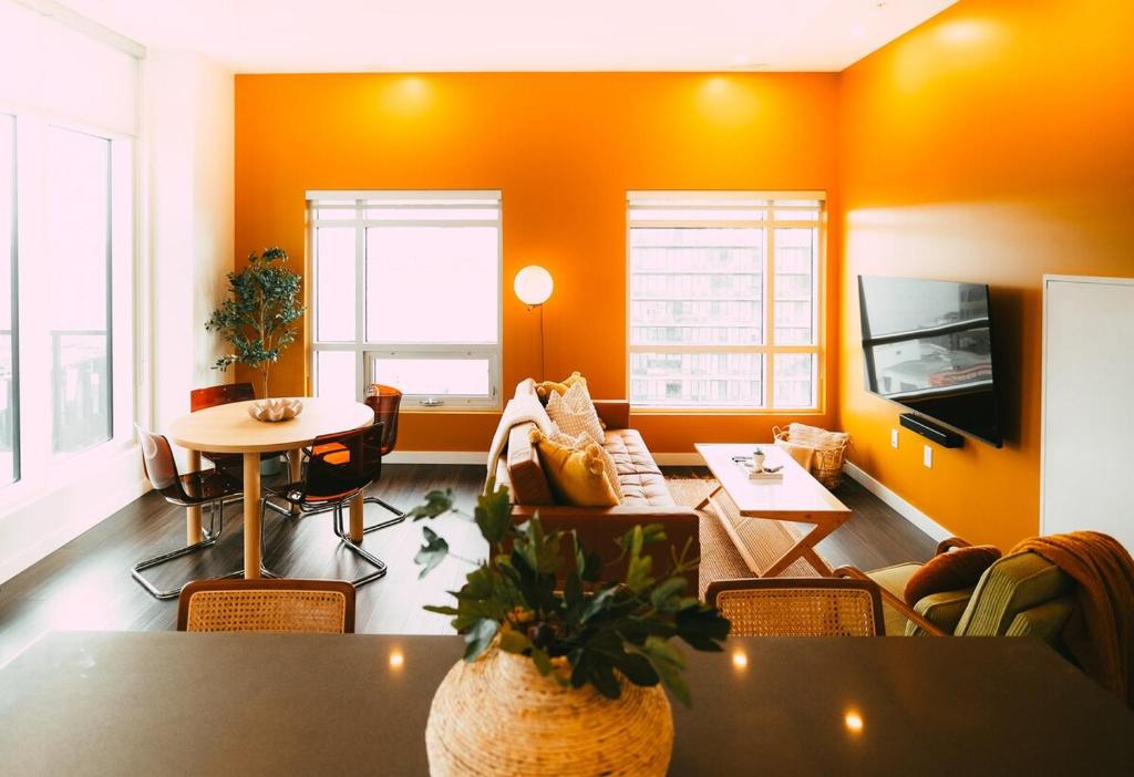 sala de estar con paredes de color naranja, sofá y mesa en Cozy 2BR Penthouse Downtown - Parking Included, en Halifax