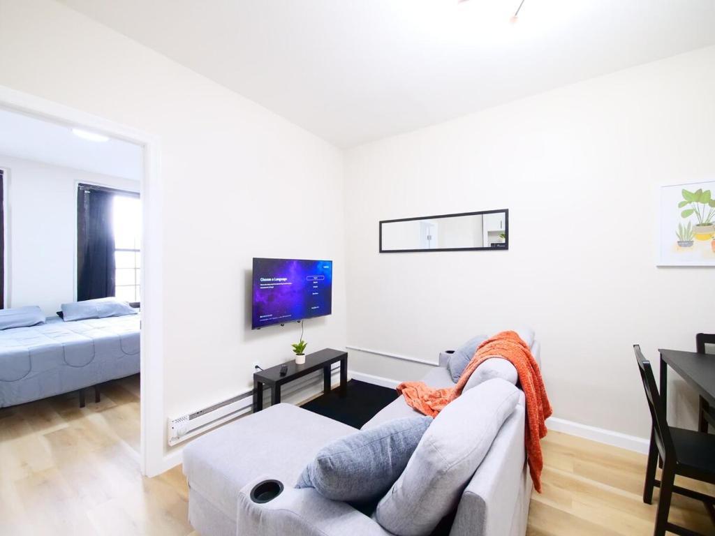 a white living room with a couch and a tv at Cozy 1BR Getaway with Wifi - Mins to NYC in Paterson