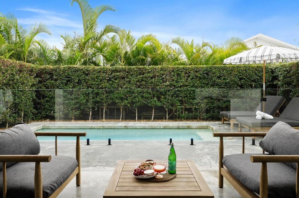 Nalu Beach House - Kingscliff Getaway by uHoliday في كينغسكليف: مسبح مع كرسيين وطاولة مع مشروب