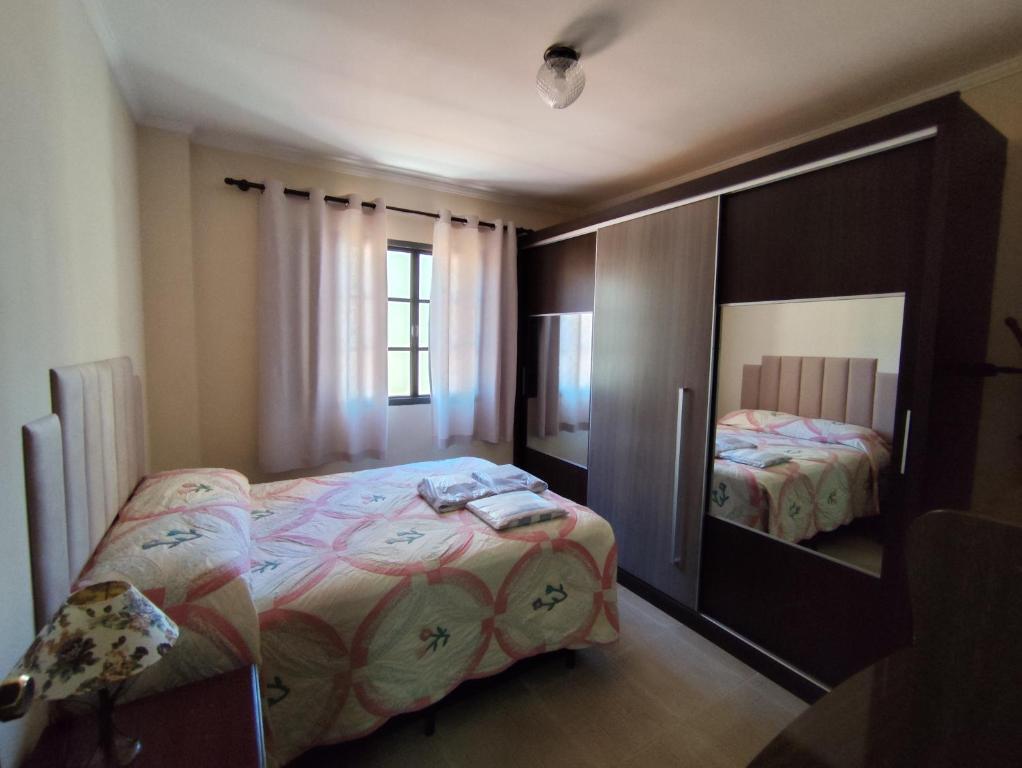 a bedroom with a bed and a large mirror at Apartamento aconchegante no centro da cidade in Serra Negra
