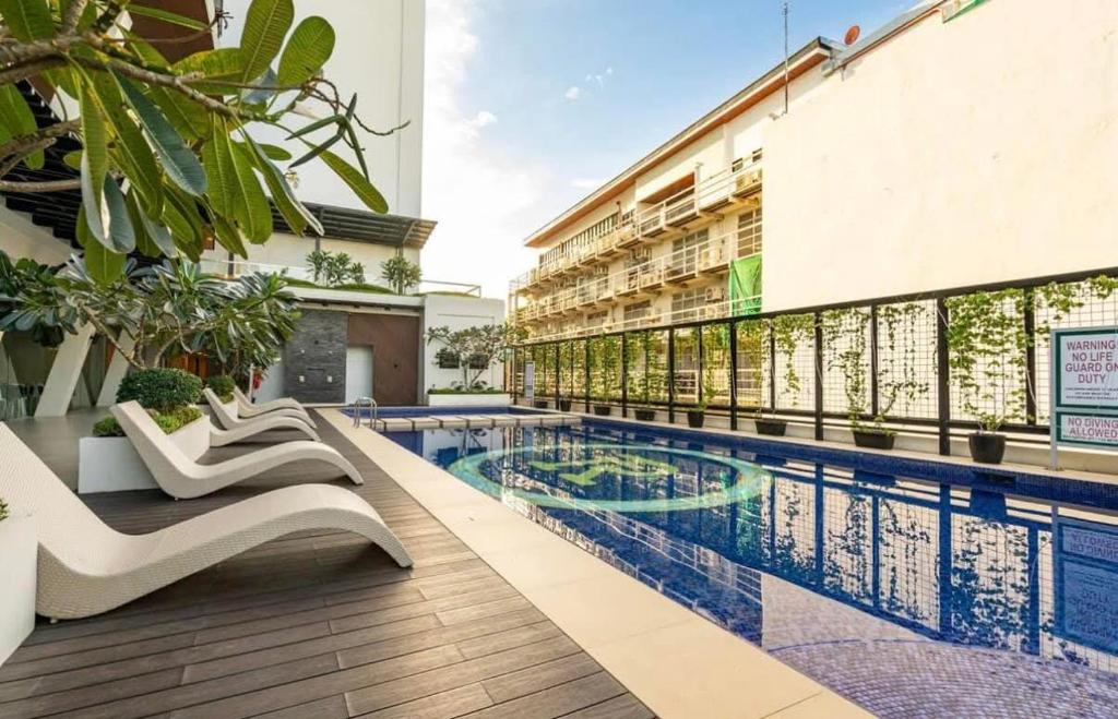 a hotel swimming pool with lounge chairs next to a building at Ivory Residences in Davao City