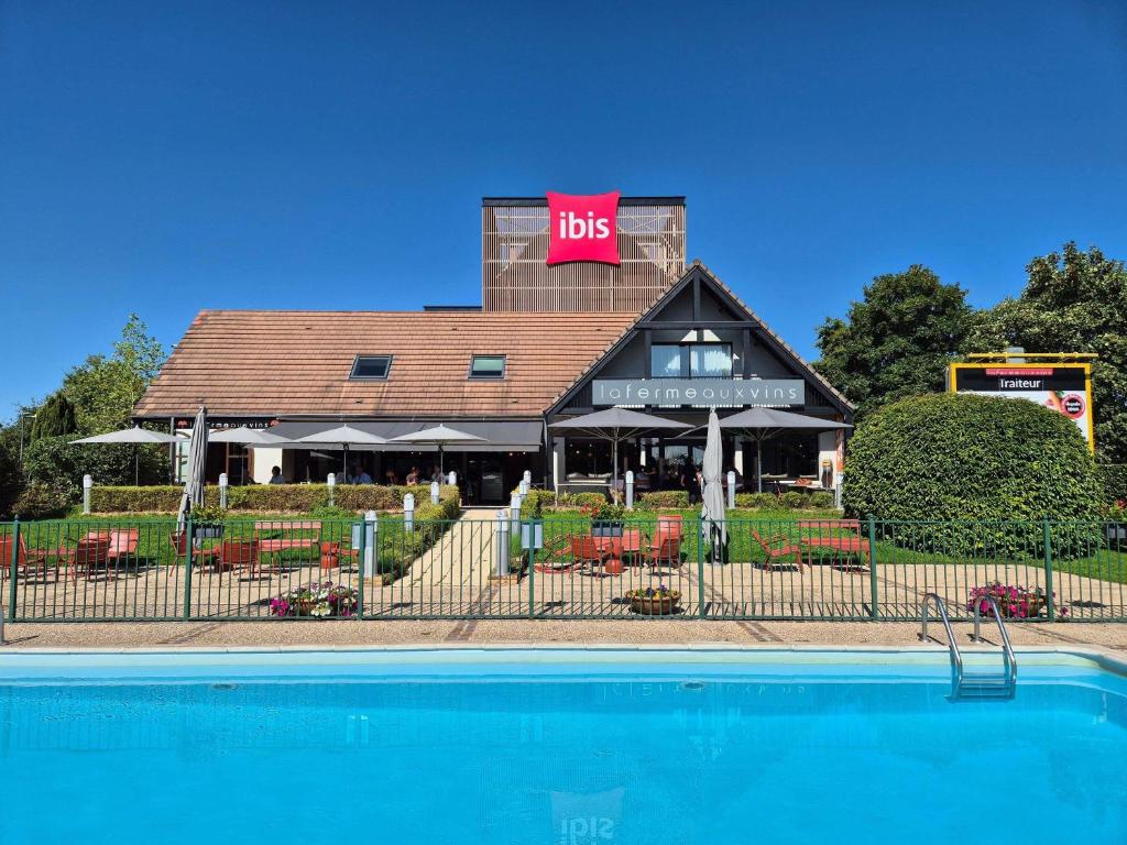 a restaurant with a pool in front of a building at ibis Beaune La Ferme Aux Vins in Beaune