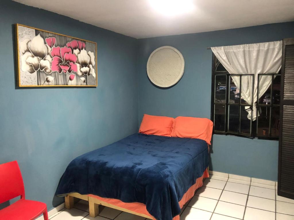 a bedroom with a bed and a red chair at Habitacion llena de paz in Tonalá