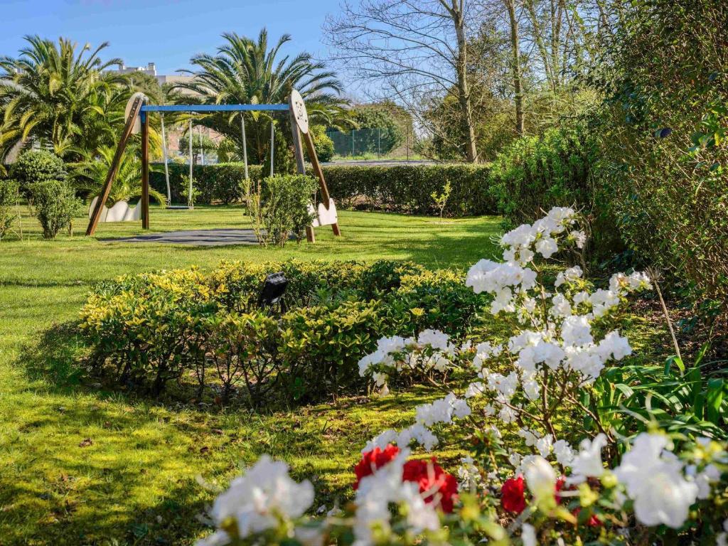 un parque con columpios y flores en Novotel Porto Gaia, en Vila Nova de Gaia