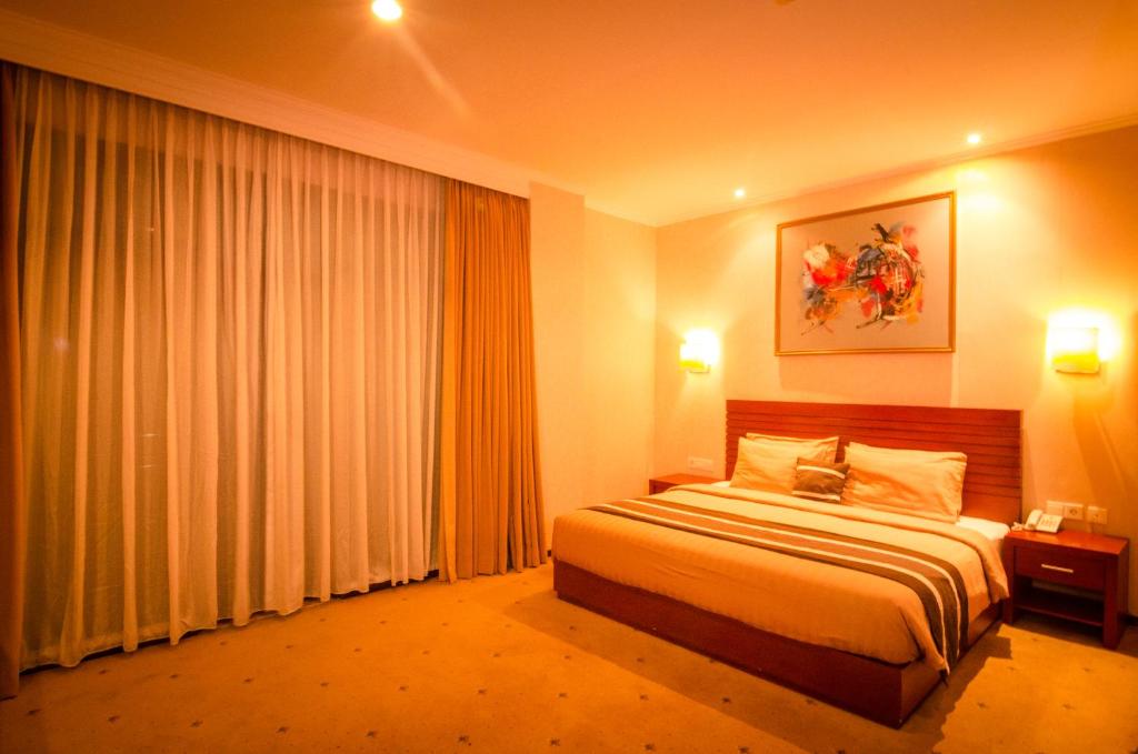 a hotel room with a bed and a large window at Bali Paradise City Hotel in Denpasar