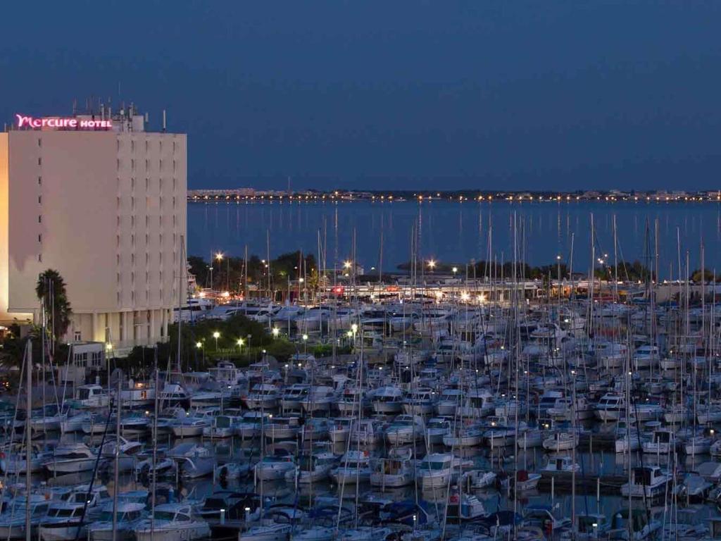 a group of boats parked in a harbor at night at Mercure Port La Grande Motte in La Grande-Motte