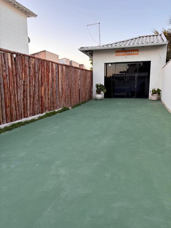 a backyard with a fence and a green driveway at Bangalô MAR & SOL in Saquarema