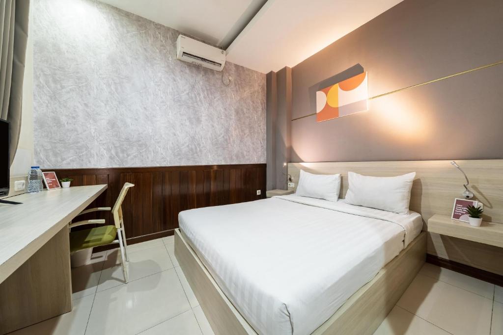 a small bedroom with a bed and a desk at Cove Ananya in Surabaya
