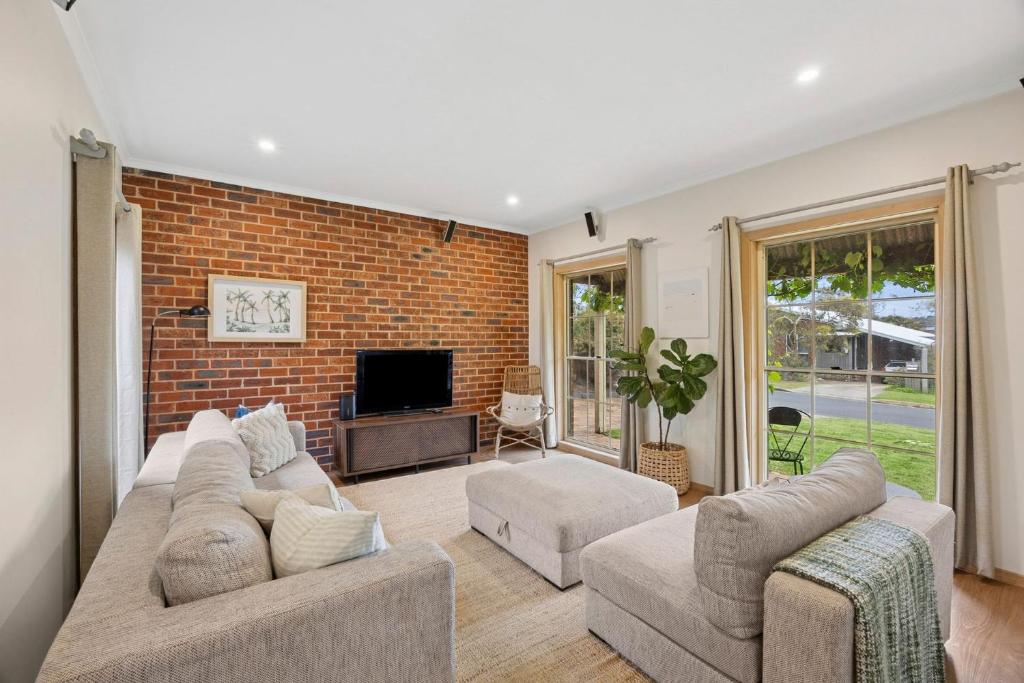 un soggiorno con 2 divani e un muro di mattoni di Riviera Retreat, Coastal Comfort Near Jan Juc Surf Beach a Bellbrae