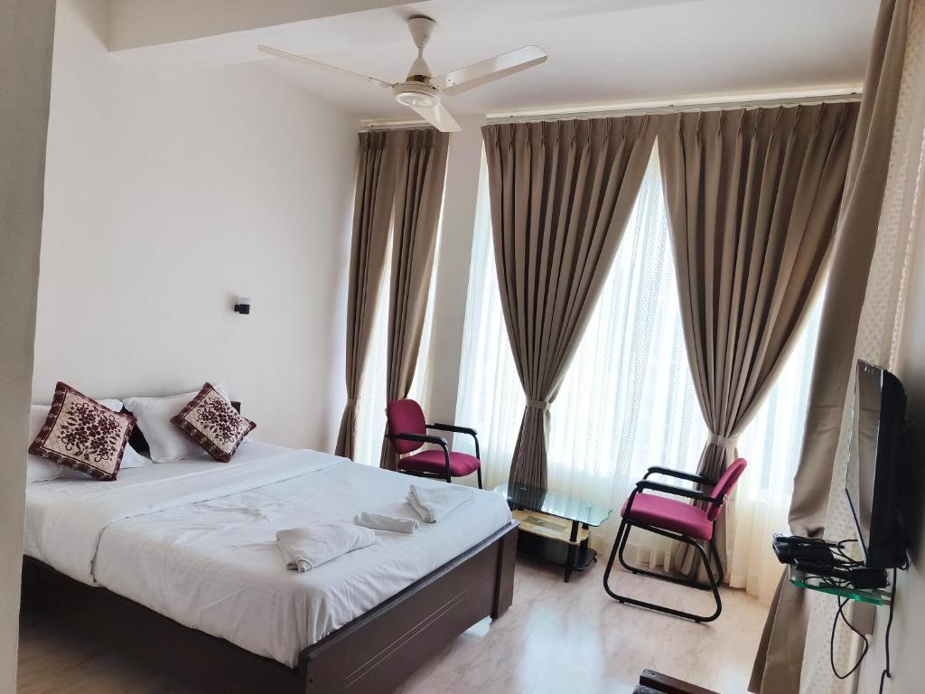 ein Schlafzimmer mit einem Bett und zwei Stühlen und einem Fernseher in der Unterkunft The Thekkady Haritham Residency in Thekkady