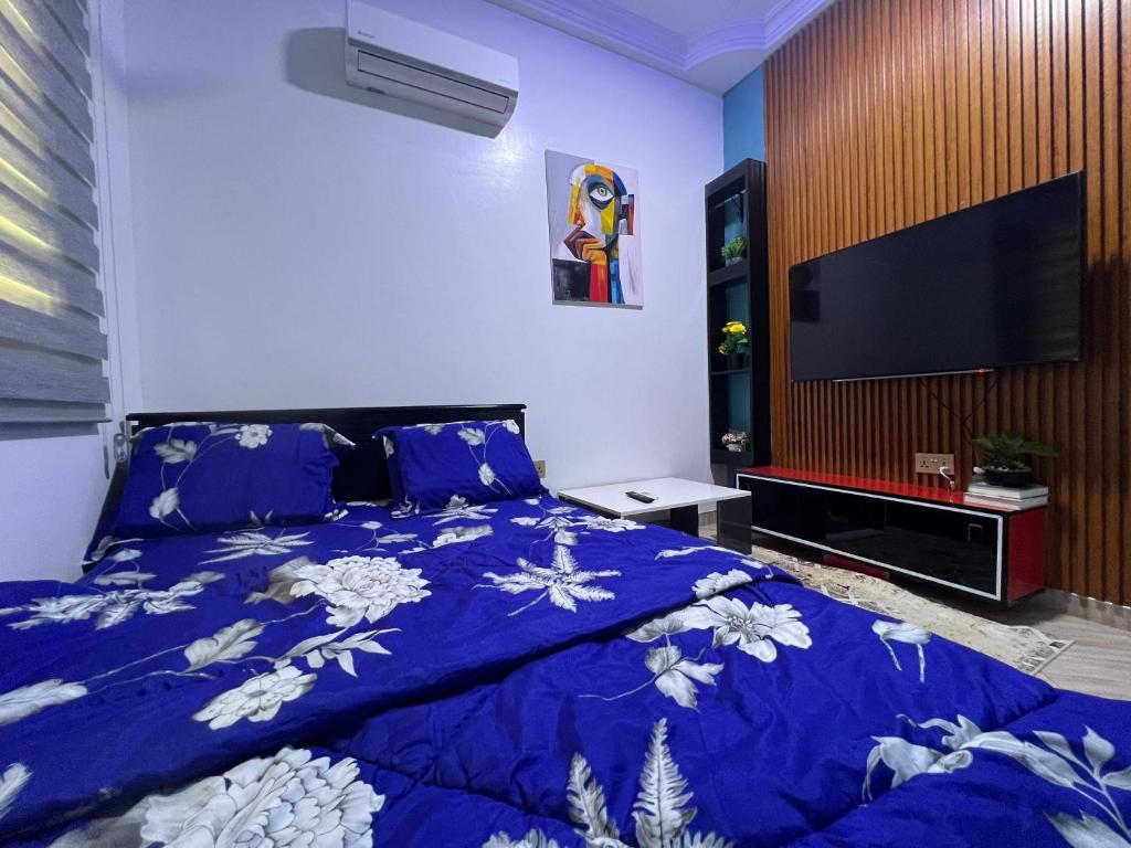 Schlafzimmer mit einem Bett mit blauer Decke und einem TV in der Unterkunft Dubai Dollar Beach Resorts in Tema