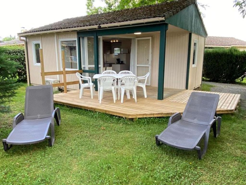 a cabin with a table and chairs on a deck at Mobil home avec terrasse à Gurmençon - API-1-52-612 in Gurmençon
