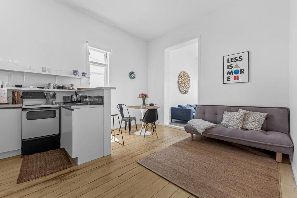 uma cozinha e sala de estar com um sofá e uma mesa em Bespoke Stays - Rustic Stanley Bay Apartment em Auckland