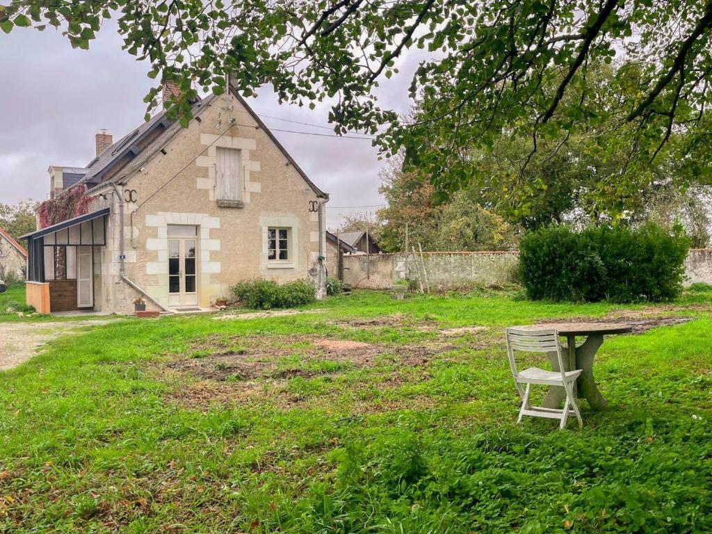 a chair sitting on the grass in front of a house at Gîte à Manthelan : Confort et Charme, Jardin, Wi-Fi - FR-1-381-639 in Monfoué