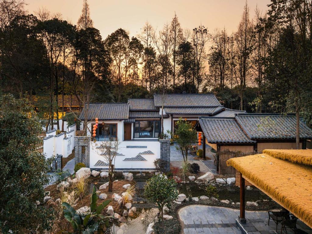 een Aziatisch huis met een tuin ervoor bij Chengdu Xiaoya Yard Hot Spring Hotel,Enjoy Soaking in natural hot springs,Traditional Chinese afternoon tea,Exquisite fruit platter in Longqiao