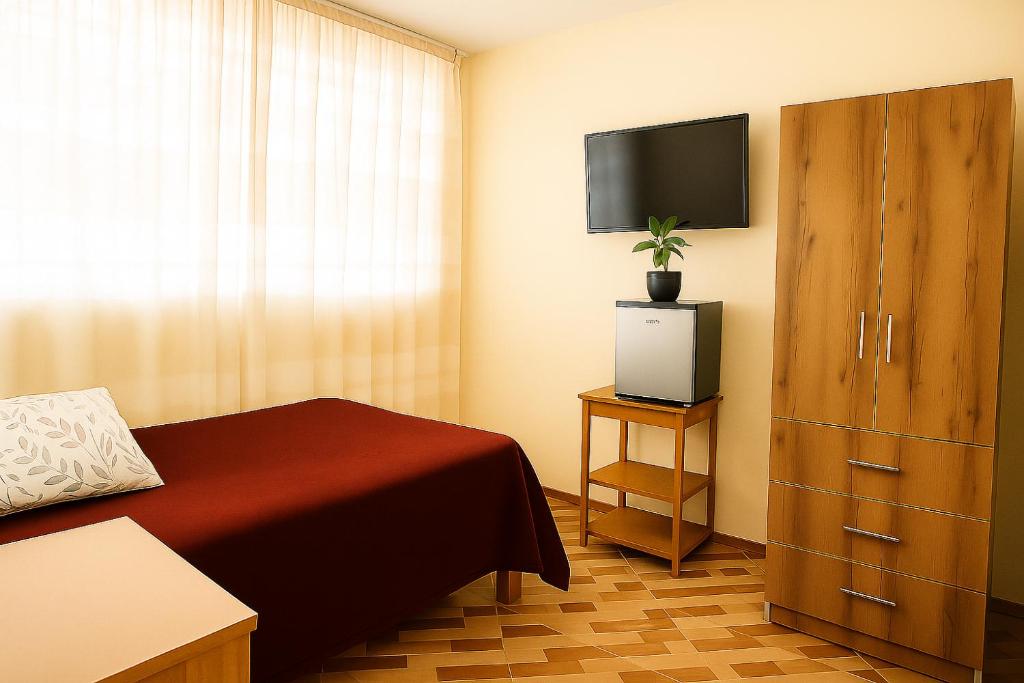 a bedroom with a bed and a dresser with a television at Departamento amoblado en primer piso 200 MTS a tu disposición con todos los servicios in Tacna