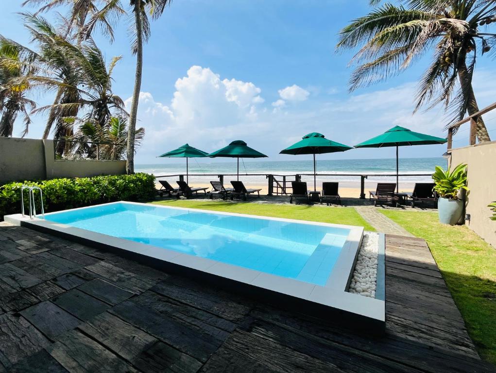 a swimming pool with the beach in the background at Hikka House - Thema Collection in Hikkaduwa