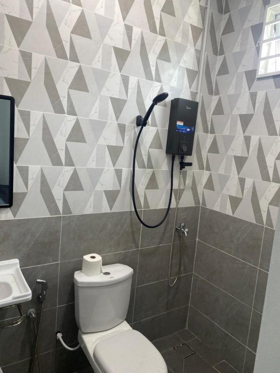 a bathroom with a toilet and a shower in it at WanZa House in Bachok