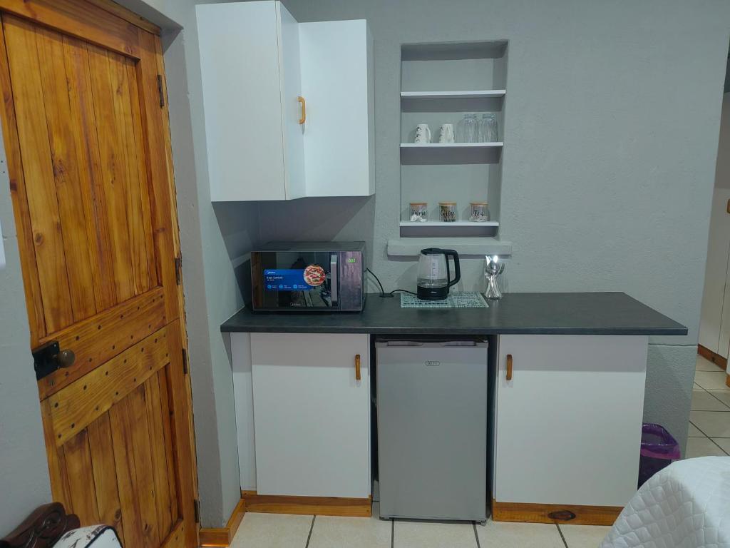 Una cocina con gabinetes blancos y una encimera negra. en WegkruiperQ, en Beaufort West