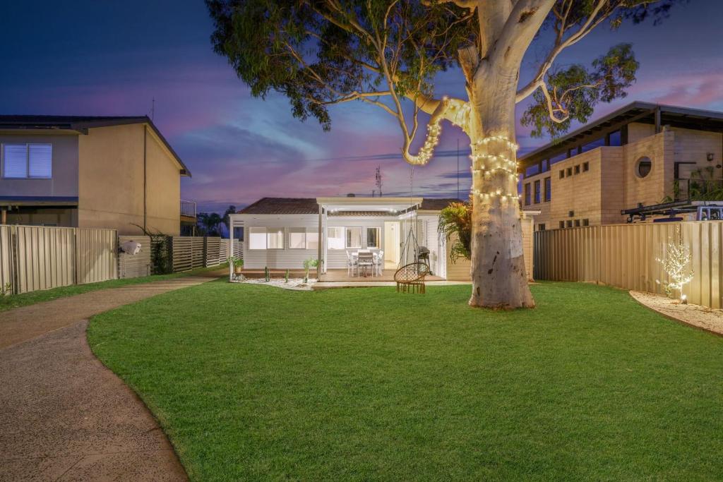a house with a tree in a yard at Casa Esperanza by Experience Jervis Bay in Vincentia