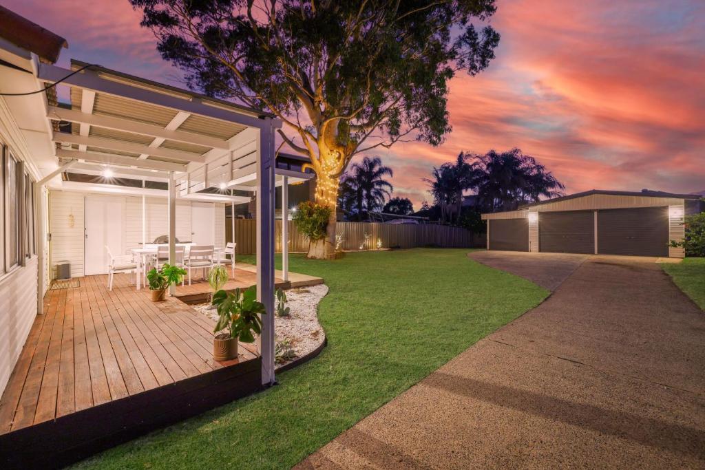 a backyard with a deck with a table and a tree at Casa Esperanza by Experience Jervis Bay in Vincentia