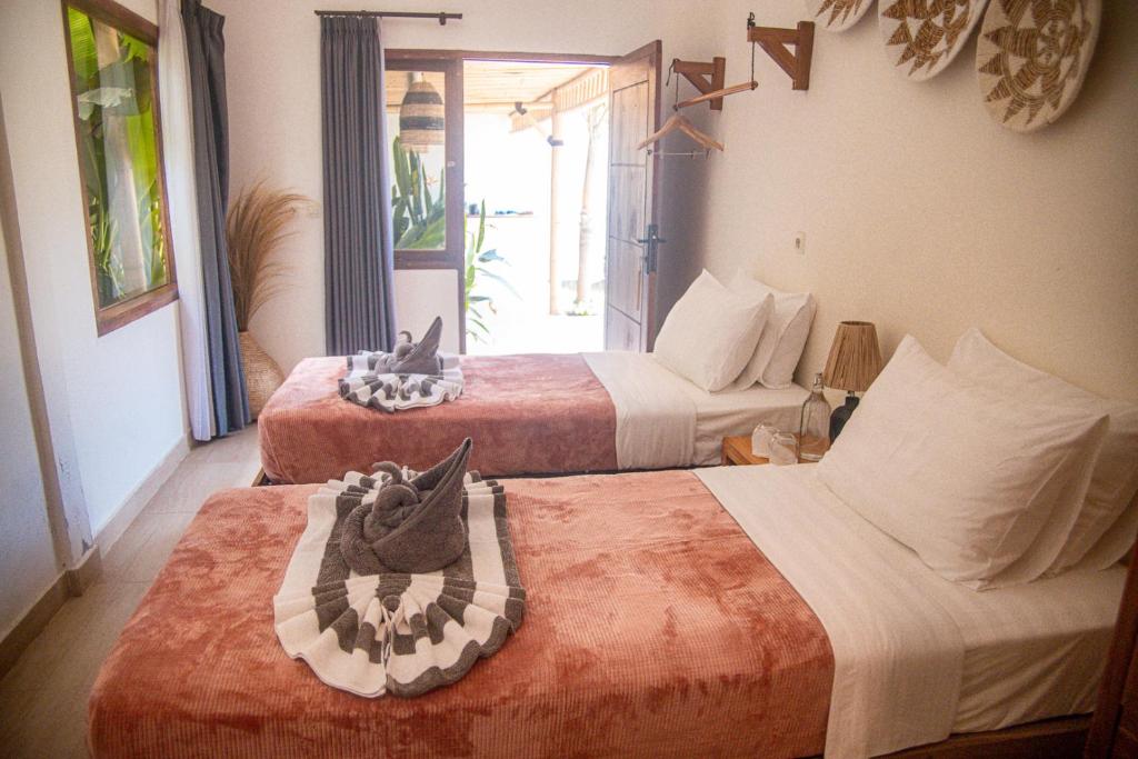 a hotel room with two beds and a window at Masaya Retreat Lombok in Kuta Lombok