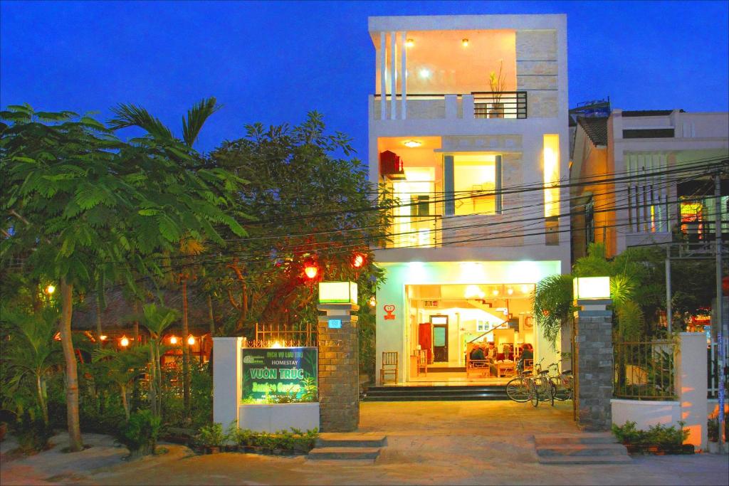 un edificio blanco con un montón de árboles delante de él en Bamboo Garden Homestay, en Hoi An