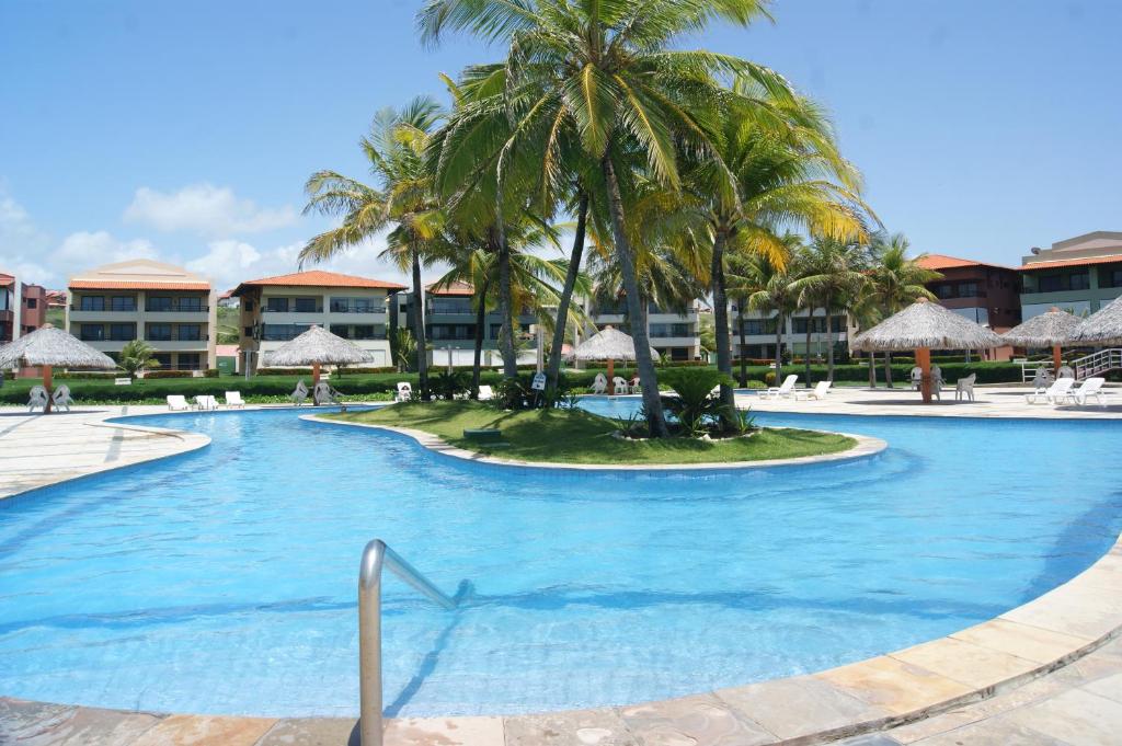 uma grande piscina com palmeiras e edifícios em Aquaville Resort em Aquiraz