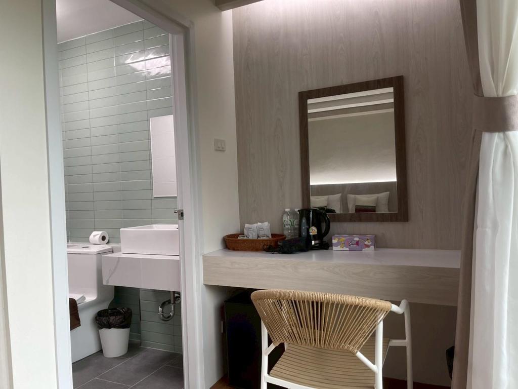 een badkamer met een wastafel, een spiegel en een stoel bij Salty Sand Krabi Hotel in Ban Khlong Haeng