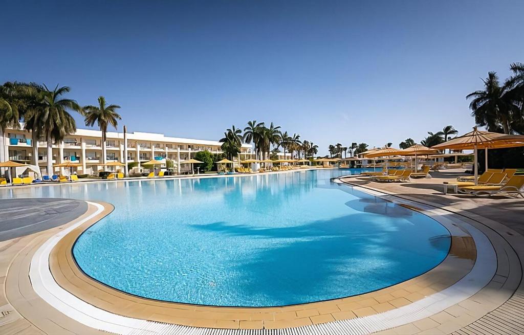 a large swimming pool in a resort with palm trees at JAZ Royal Palmariva in Hurghada