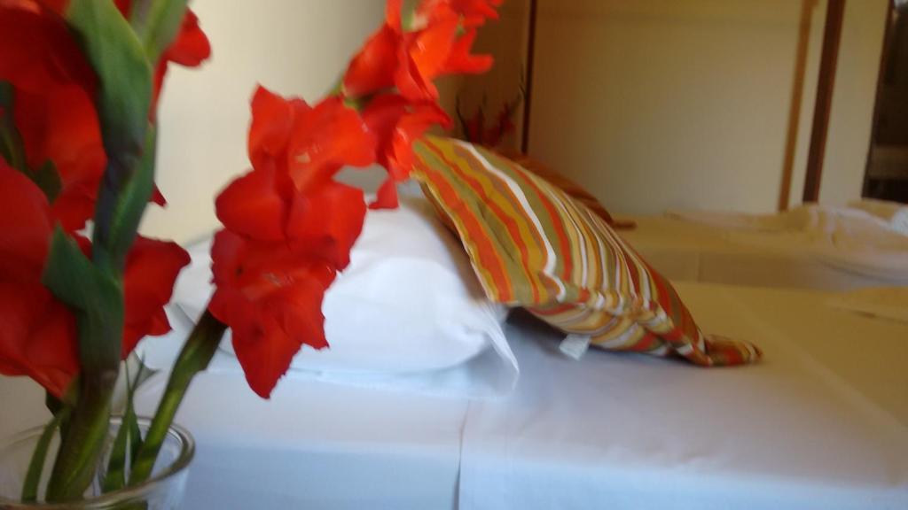 un jarrón lleno de flores rojas en una mesa en Pousada Jambo, en Trancoso