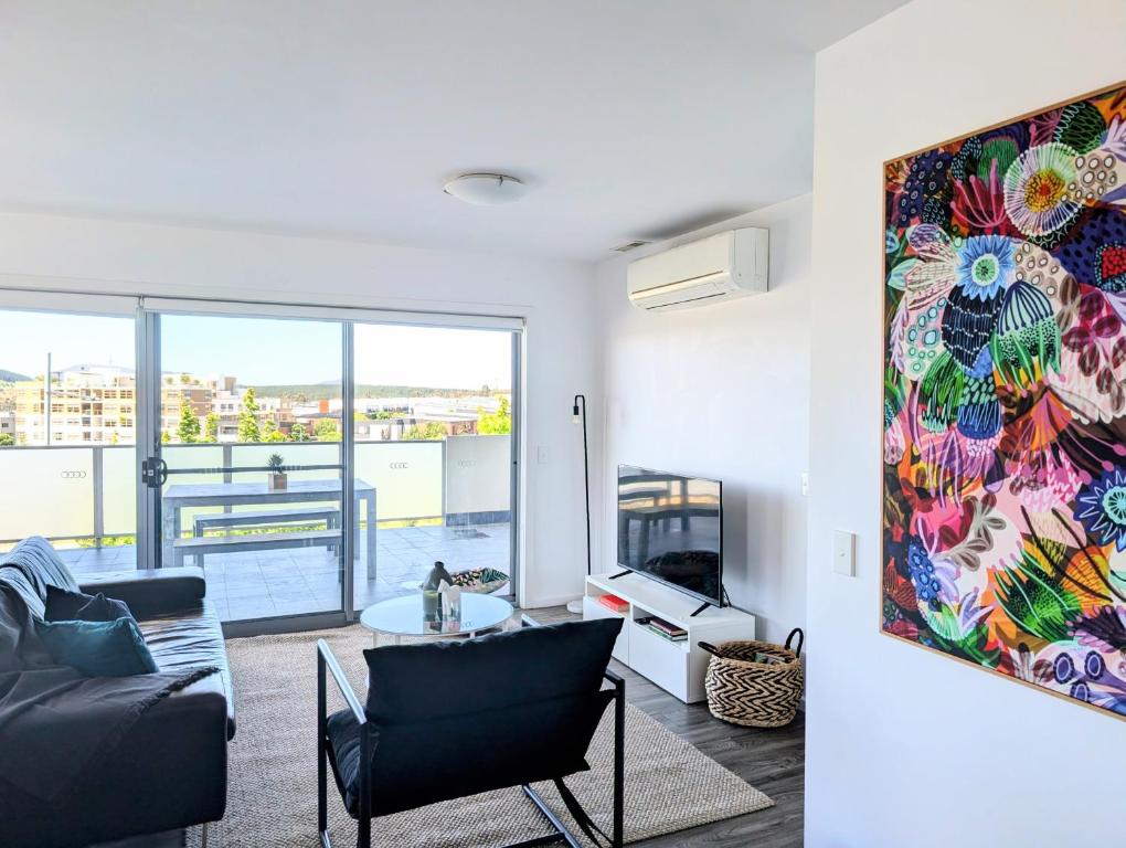 a living room with a couch and a painting on the wall at Modern & Relaxed Apartment, Great Views @Wright in Weston Creek