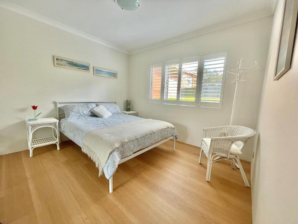 Un dormitorio con una cama y dos sillas y una ventana. en Cronulla courtyard unit, 10 mins walk to Beach & Bay, en Cronulla