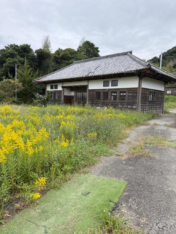 una casa vieja con un campo de flores delante de ella en Oasis Minamiboso, en Minamiboso