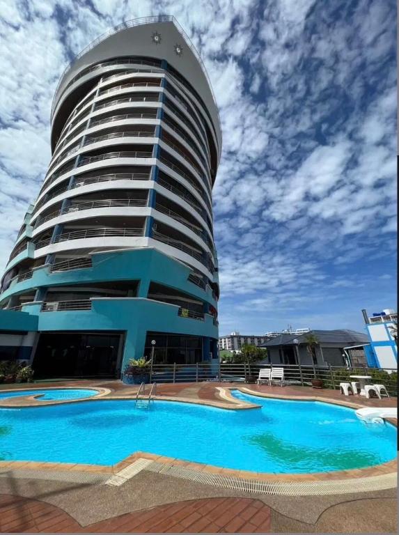 a building with a large swimming pool in front of it at Bangsaen sansuk in Ban Laem Thaen