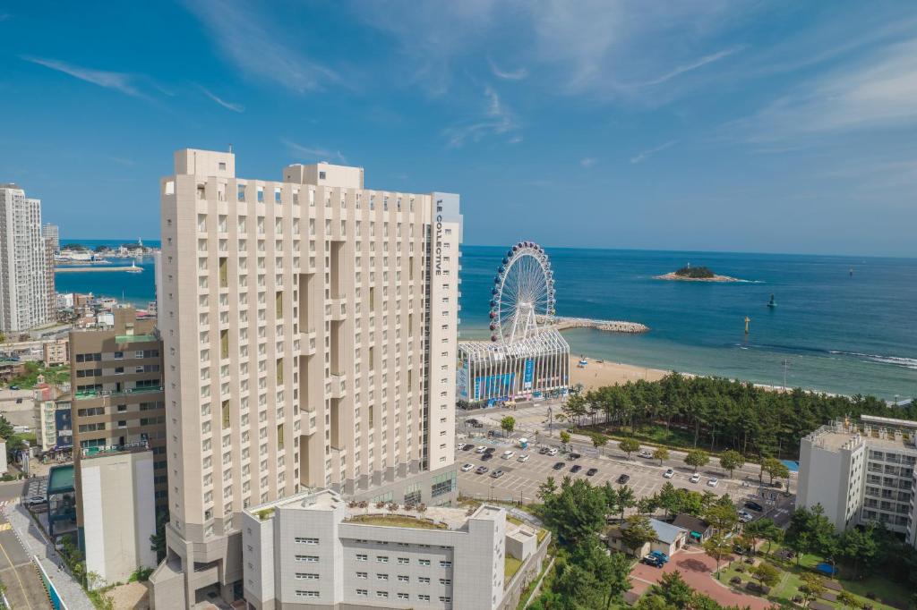 een groot wit gebouw met een achtbaan in de oceaan bij Richeville Signature Hotel and Residence in Puwŏl-li