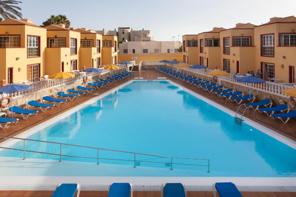 ein großer Pool mit Stühlen und Sonnenschirmen in der Unterkunft Apartamentos Maxorata Beach in Corralejo