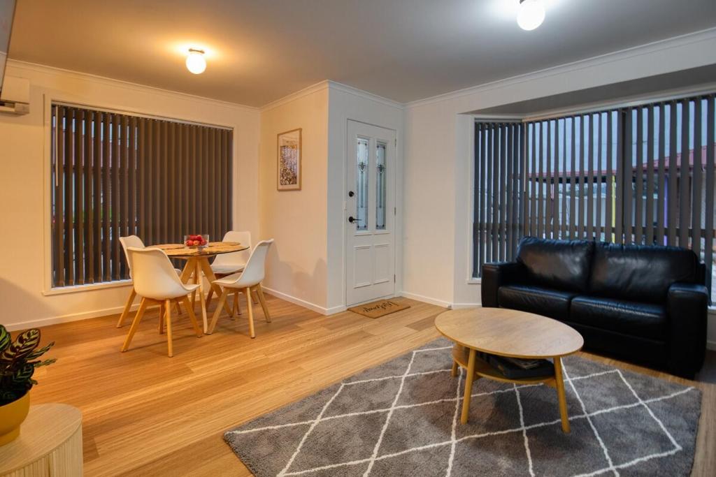 a living room with a black leather couch and a table at Sorell Gateway Villa in Sorell