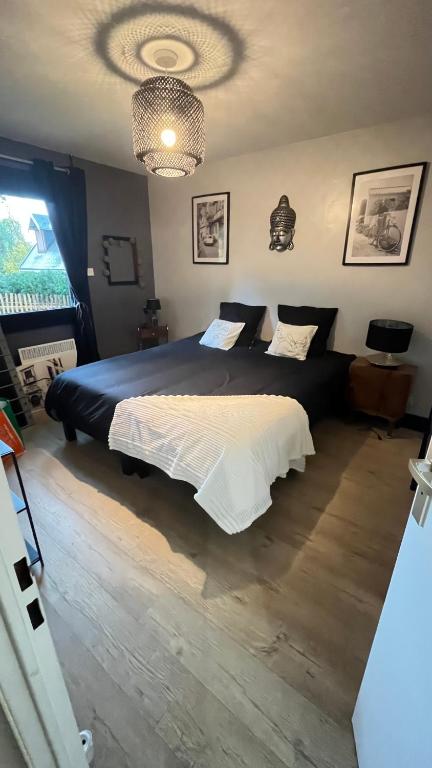 a bedroom with a large bed and a chandelier at Les dunes le Lima in Quend-Plage