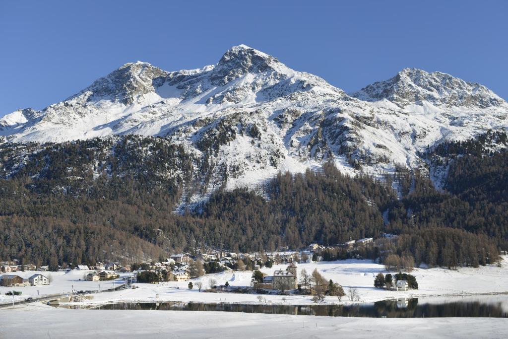 una montaña cubierta de nieve con una ciudad frente a un lago en Attic Lake View with Free Parking, en Silvaplana