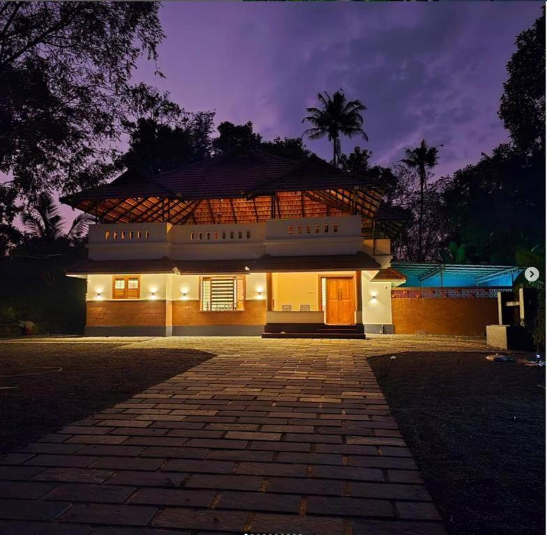 a house with a lit up building at night at Acrewood Farmhouse - Pool Villa in Vāzhākulam