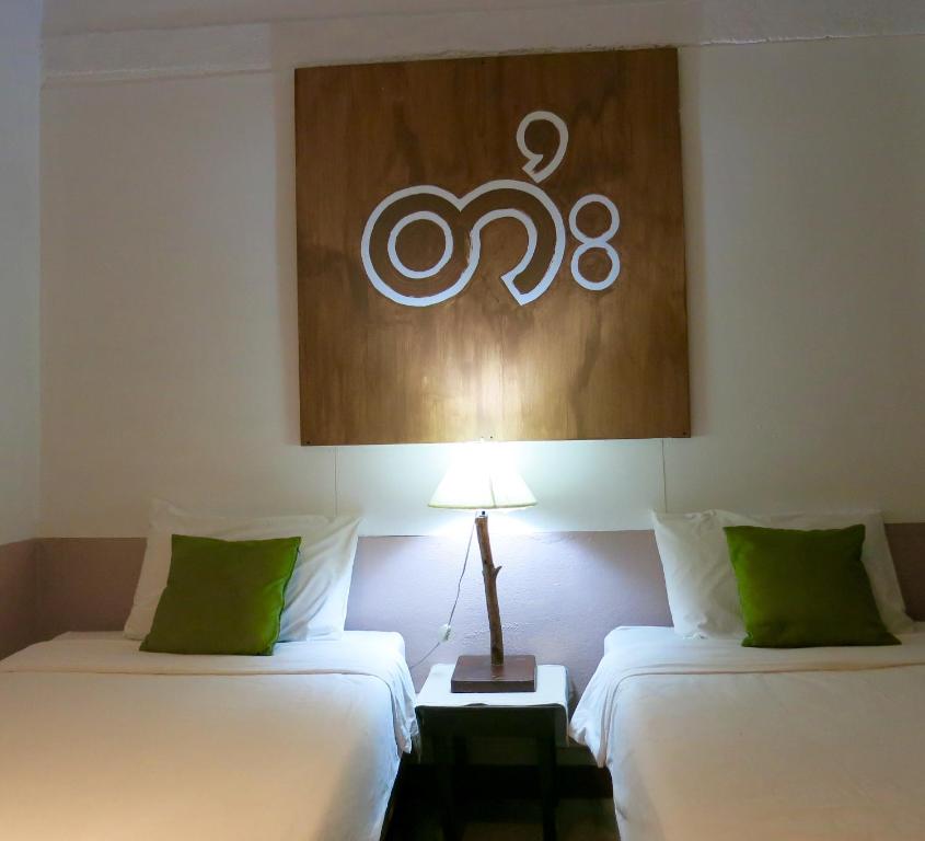 two beds in a room with a sign on the wall at Yoont Hotel in Ban Khun Yuam